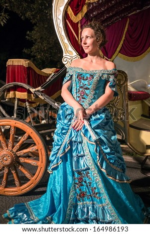 stock-photo-the-beautiful-girl-in-blue-old-fashioned-dress-with-fan-near-the-carriage-164986193.jpg