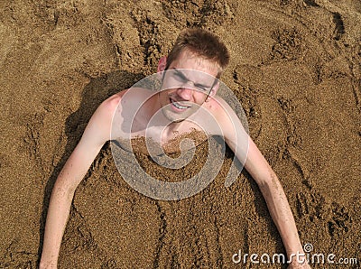 young-man-buried-sand-18903182.jpg