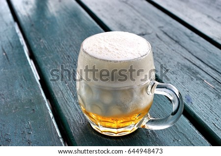 stock-photo-half-full-glass-of-beer-with-foam-on-wooden-table-644948473.jpg