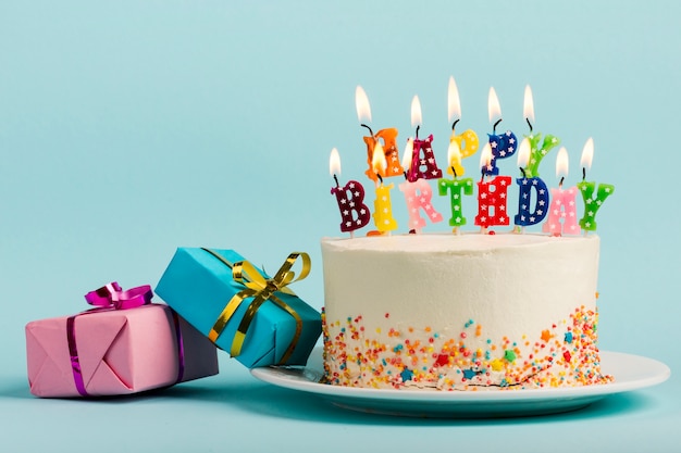 two-gift-boxes-near-cake-with-happy-birthday-candles-against-blue-backdrop_23-2148190488.jpg